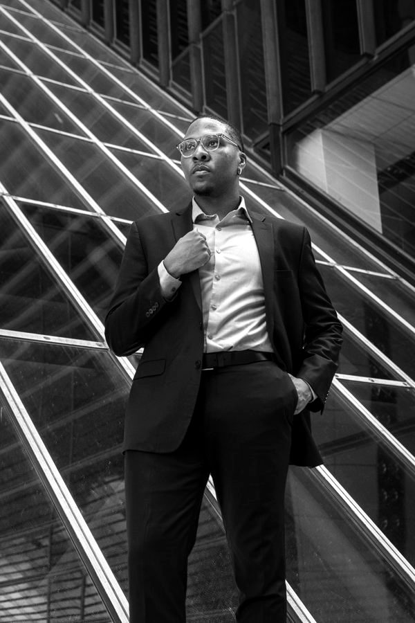 Black and white portrait of Gabriel Walker adjusting his collar.