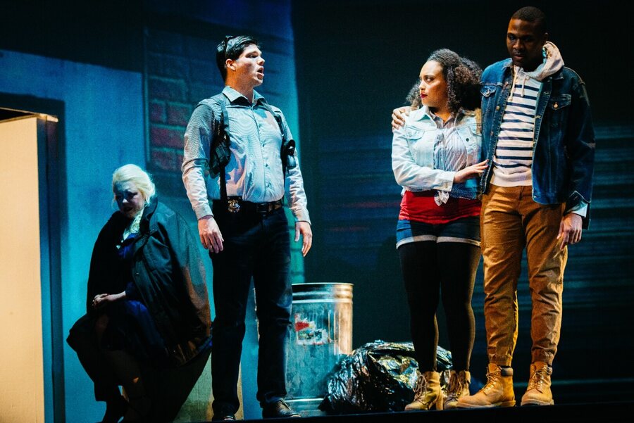 Masetto and Zerlina in modern dress under blue light in the street scene.